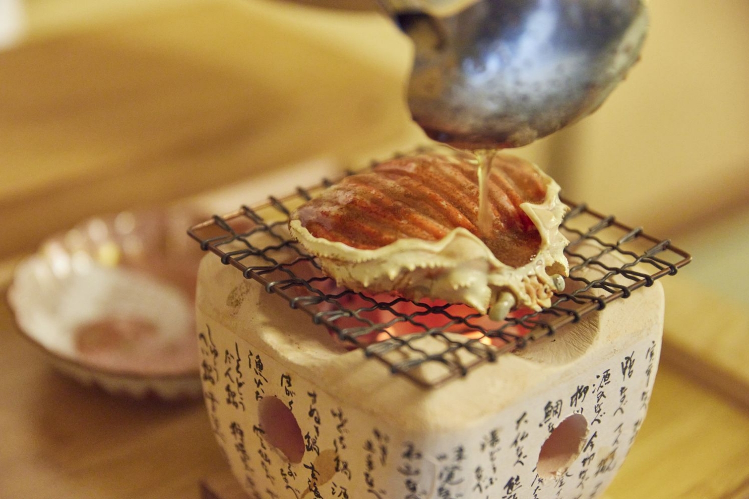 小さな七輪で蟹の甲羅を焼く写真