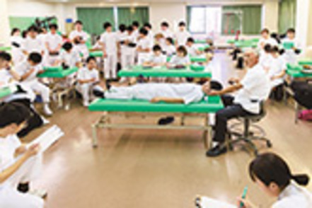 高崎健康福祉大学 実習用のベッドが並ぶほか、指導用のトリートメントテーブルが置かれ、教員の動きにならって2人1組での実習を行います