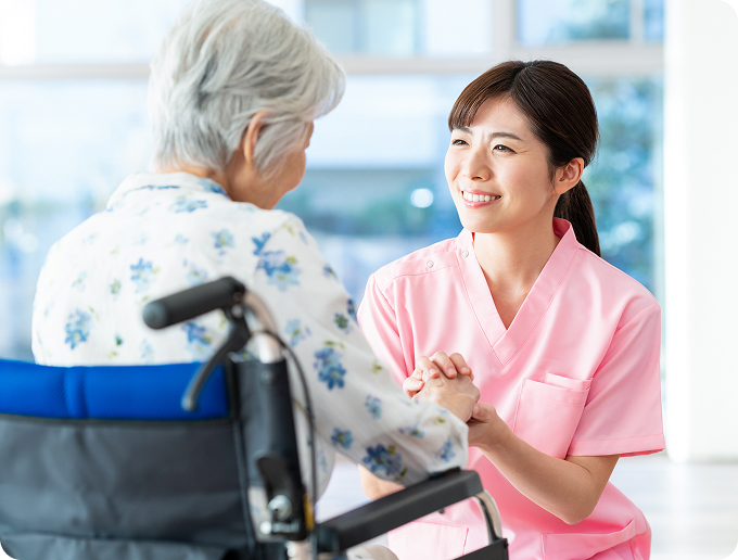 車椅子に乗った高齢者と話す看護師
