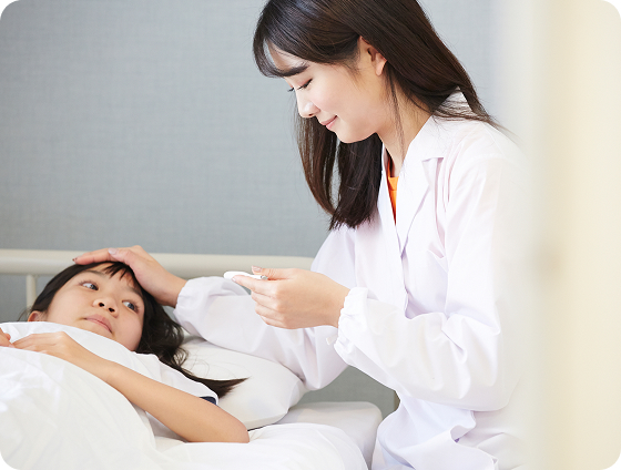 ベッドに横たわる児童の頭に手を添える養護教諭